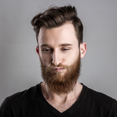 Sad and unhappy young man isolated on gray backround