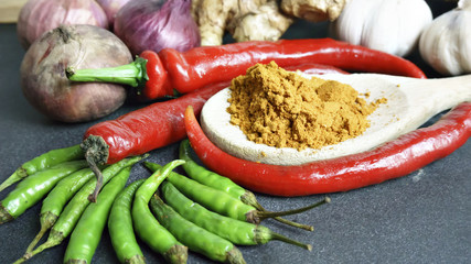 Asian cuisine ingredients - red pepper  garlic  shallots  green pepper and turmeric powder on black background