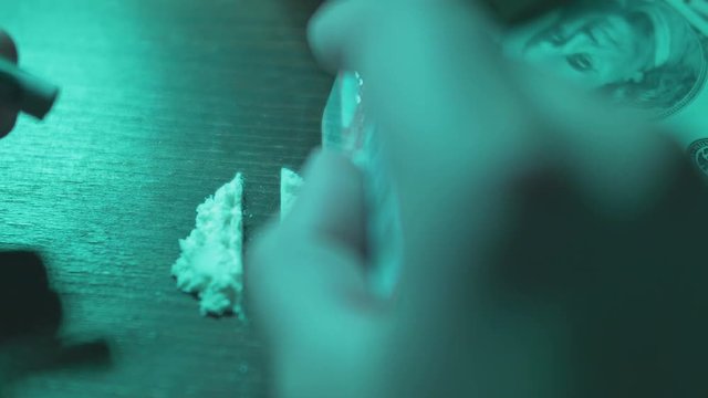 Hand using credit card to chop cocaine. Green light.