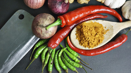 Asian cuisine ingredients - red pepper  garlic  shallots  green pepper and turmeric powder on black background