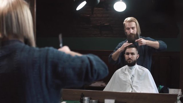 Male barber cutting hair of man in Barbershop