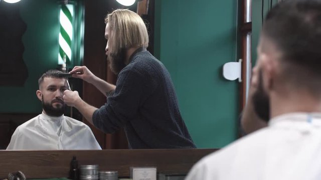 Male barber cutting hair of man in Barbershop