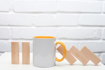 A cup of tea or coffee stop the Domino principle. Business concept. On a white wooden background. Horizontally.