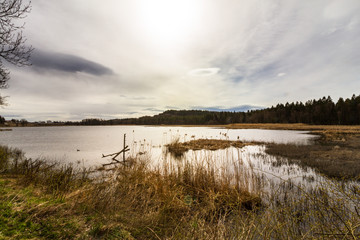 Sun behind clouds over lake, Gjennestadvannet, Stokke, Vestfold in Norway