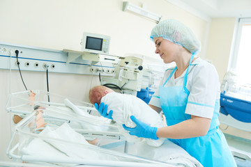 young female nurse holding a newborn baby in hospital