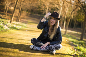 Portrait of a beautiful woman in hat on the park sitting on the floor.