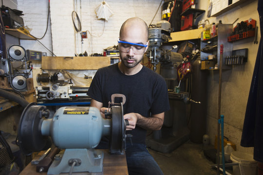 Mixed Race man using machinery in workshop