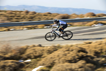 Naklejka premium Cyclist man riding mountain bike on a mountain road