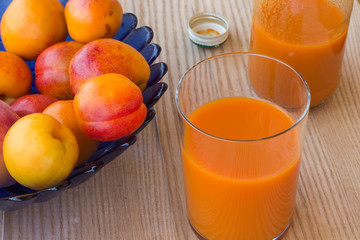Apricot juice and apricots in a blue vase on a white background