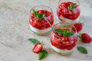 Air dessert with strawberries, mascarpone and strawberry jelly in glasses against a background of brown stone. Place for your text.