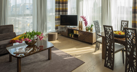 Modern decorated flat interior. Guest room. TV, tables, flowers, fruits.