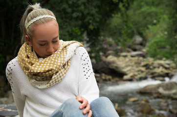 Happy young girl sitting by the rocks in a forest enjoying the quietness