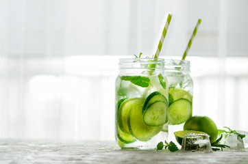 Homemade lime lemonade with cucumber, rosemary and ice, white background. Cold beverage for hot...