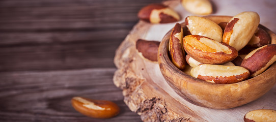 Bowl of peeled brazil nuts on wooden background with copy space