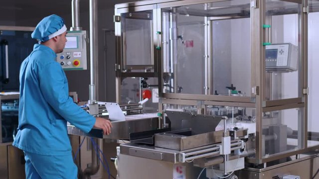 Pharmacist control pharmaceutical manufacturing process at drug factory. Pharmaceutical machine. Pharmaceutical worker check pharmaceutical production line. Health care industry. Pharmacy equipment