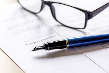 workspace with document, glasses and pen for sign for businessman day