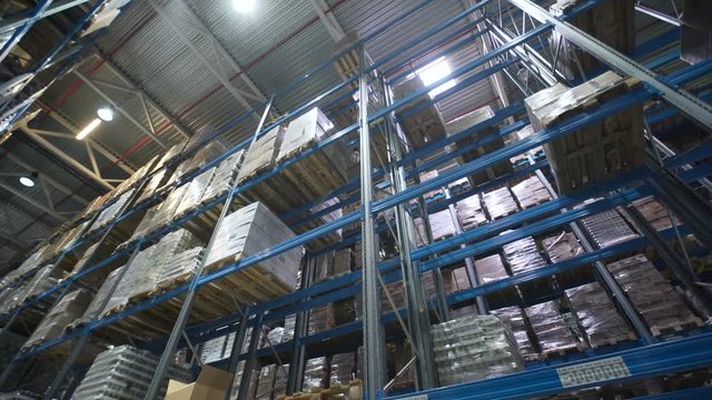 Camera moving between palettes with ordered goods and materials at warehouse. Large warehouse logistics terminal. Multi level storage with racks full of goods and materials