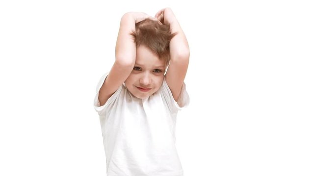 Boring Caucasian elementary-school aged boy standing on white background taking head in hands in slowmotion