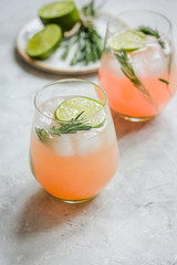 sliced lime, rosemary, plate and juice in glass on stone table background