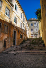 Fototapeta na wymiar Steep stairs of Lisbon between historic building with rustic yellow facades