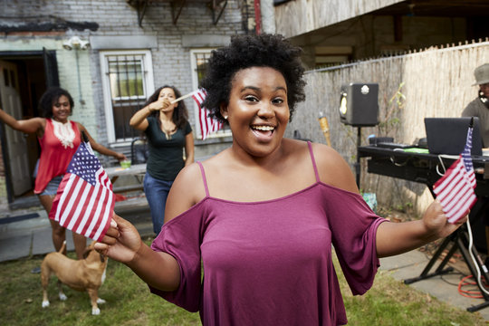 Women celebrating with American flags in backyard - Powered by Adobe