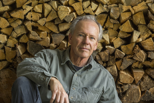 Caucasian man leaning on woodpile