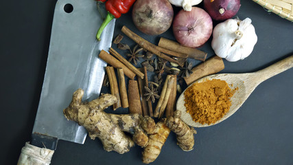 cinnamon, curry powder, garlic, onion, chili, meat cleaver on a black background, Concept cuisine Asian countries.