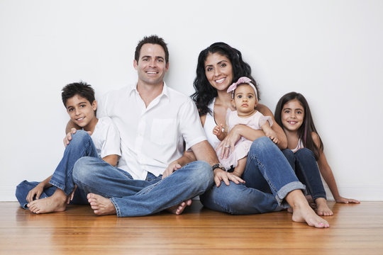 Portrait Of Smiling Mixed Race Family Sitting On Floor