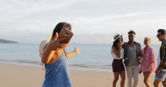 Girl Use Cell Smart Phone Welcome People Group To Take Selfie Photo On Beach, Happy Smiling Man And Woman Friends Slow Motion 60