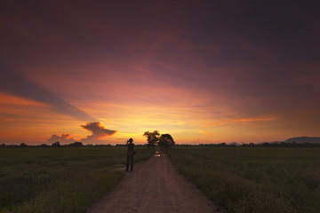 Obraz na płótnie Canvas A man capturing beautiful colors during sunrise with phone.