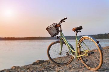 Vintage bicycle with a basket near the lake during beautiful summer sunset. Copy space.