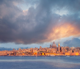 Beautiful spires and cathedral dome of Valletta under dramatic sky on the sunset