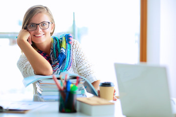 Young woman sitting at a desk among books