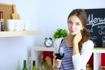 Pretty woman drinking some wine at home in kitchen
