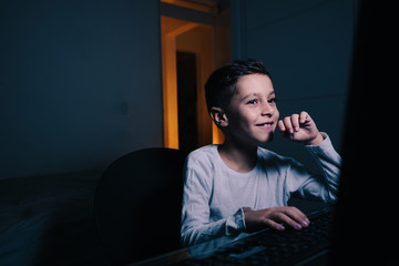 Little boy using computer at night in bedroom
