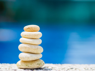 Fototapeta na wymiar Balance Stones stacked to pyramid in the soft blue water background to Spa ideas design or freedom and stability concept on rocks.