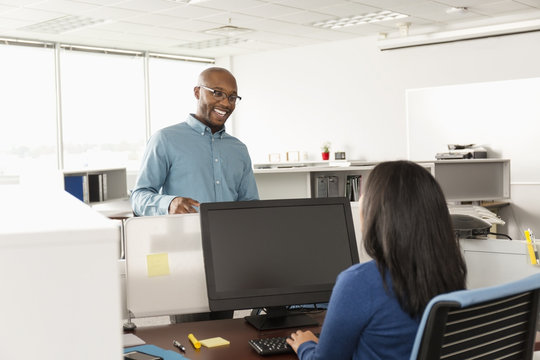 Man and woman talking near computer in office