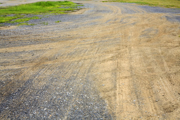 car wheel trail on the ground and gravel floor with grass field