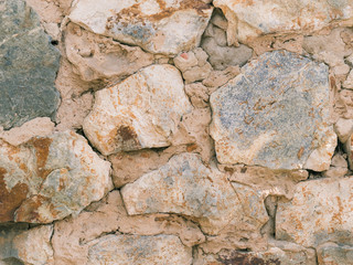 The crumbling wall of large stones with cement.