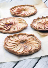 Apple pie on the thin crust with sugar and cinnamon. Apple tart with ricotta cheese and cinnamon. Round pies on the white wooden background. Apple's slices. Piece of pie.