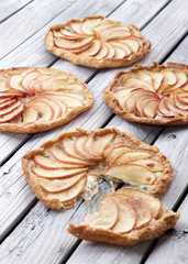 Apple pie on the thin crust with sugar and cinnamon. Apple tart with ricotta cheese and cinnamon. Round pies on the white wooden background. Apple's slices. Piece of pie.