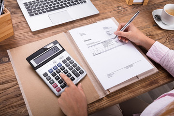 Businesswoman Calculating Tax On Desk