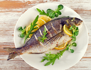 Fried sea bream on plate with  a lemon.