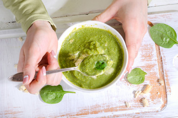 Young Woman hands with Bowl of green spinash soup
