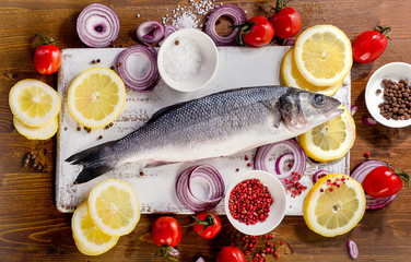 Raw seabass with spices, salt, lemon and onion slices.  Healthy eating concept.