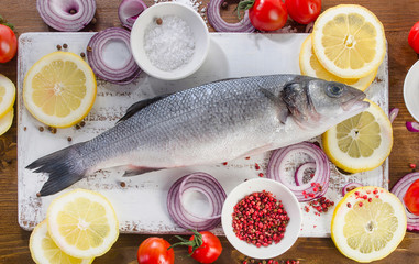 Raw seabass with  spices, salt, lemon and onion slices.  Healthy eating, diet concept.