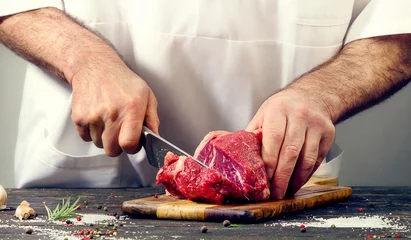 Tuinposter Vlees Chef-kok die rundvlees snijdt