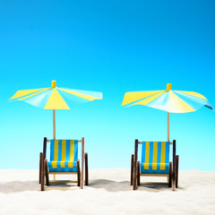 Two sunbeds at the beach on background of blue sky