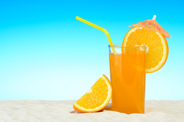 A glass of orange juice on the beach