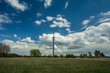 transmitter mast with green meadow and a sky with clouds
